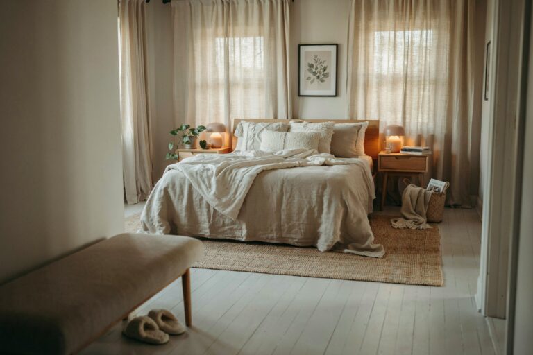 cozy neutral bedroom with layered linen bedding, warm wood nightstands, and soft natural light